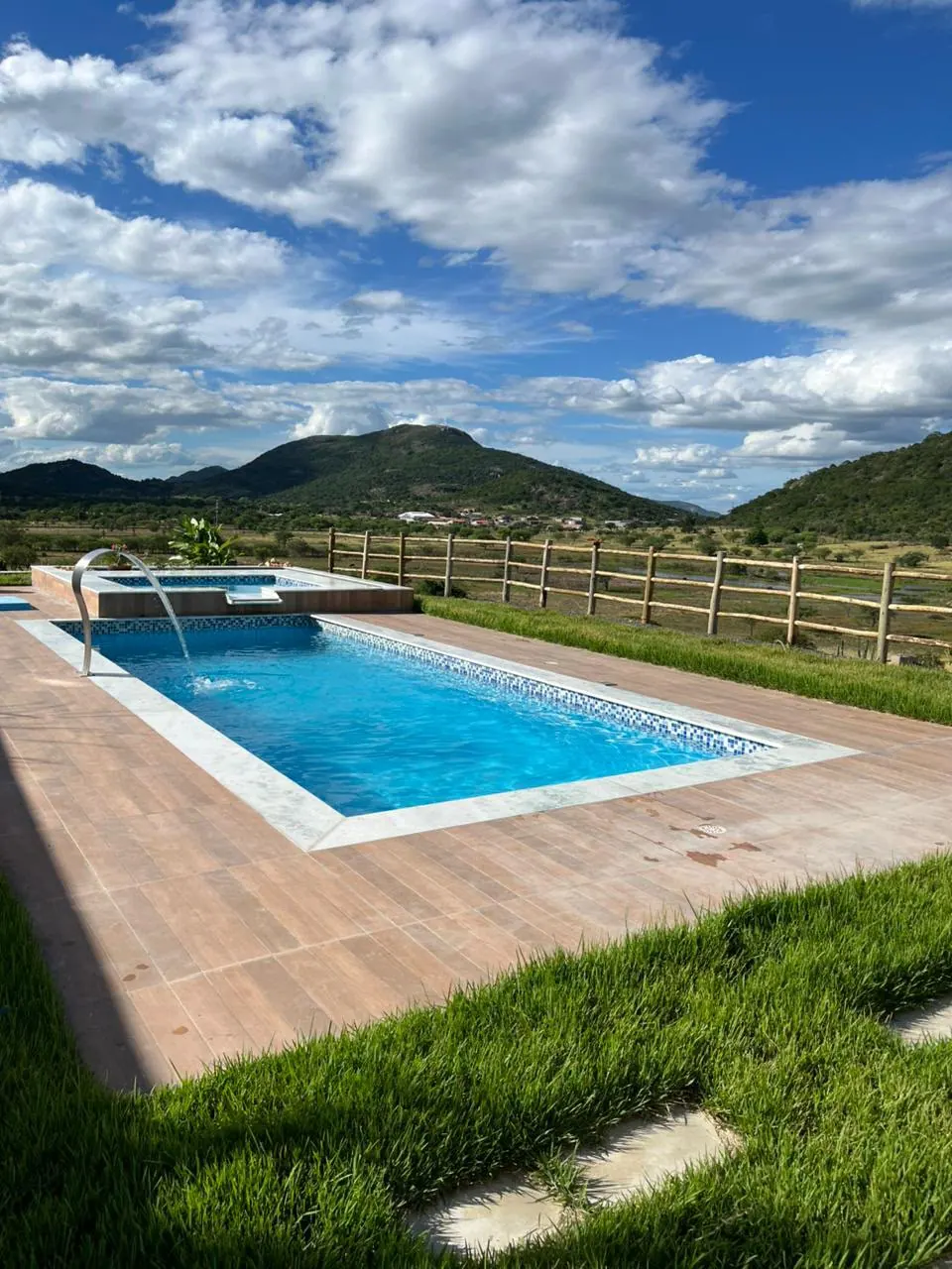 Piscina de fibra entregue, com deck, cascata e serra ao fundo